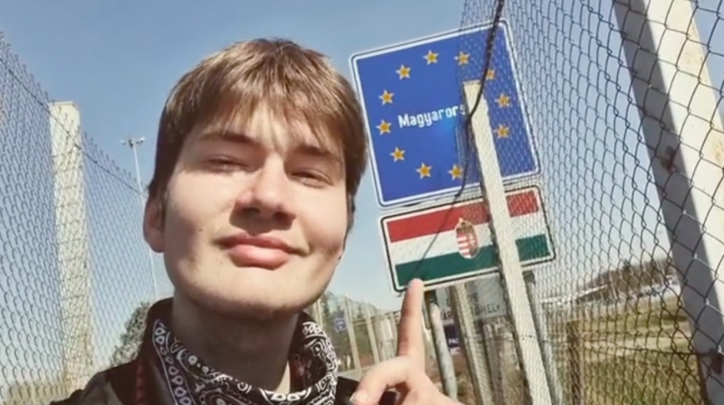 monokov, un ragazzo con un ciuffo biondo sulla sinistra indica il cartello al confine con la Croazia