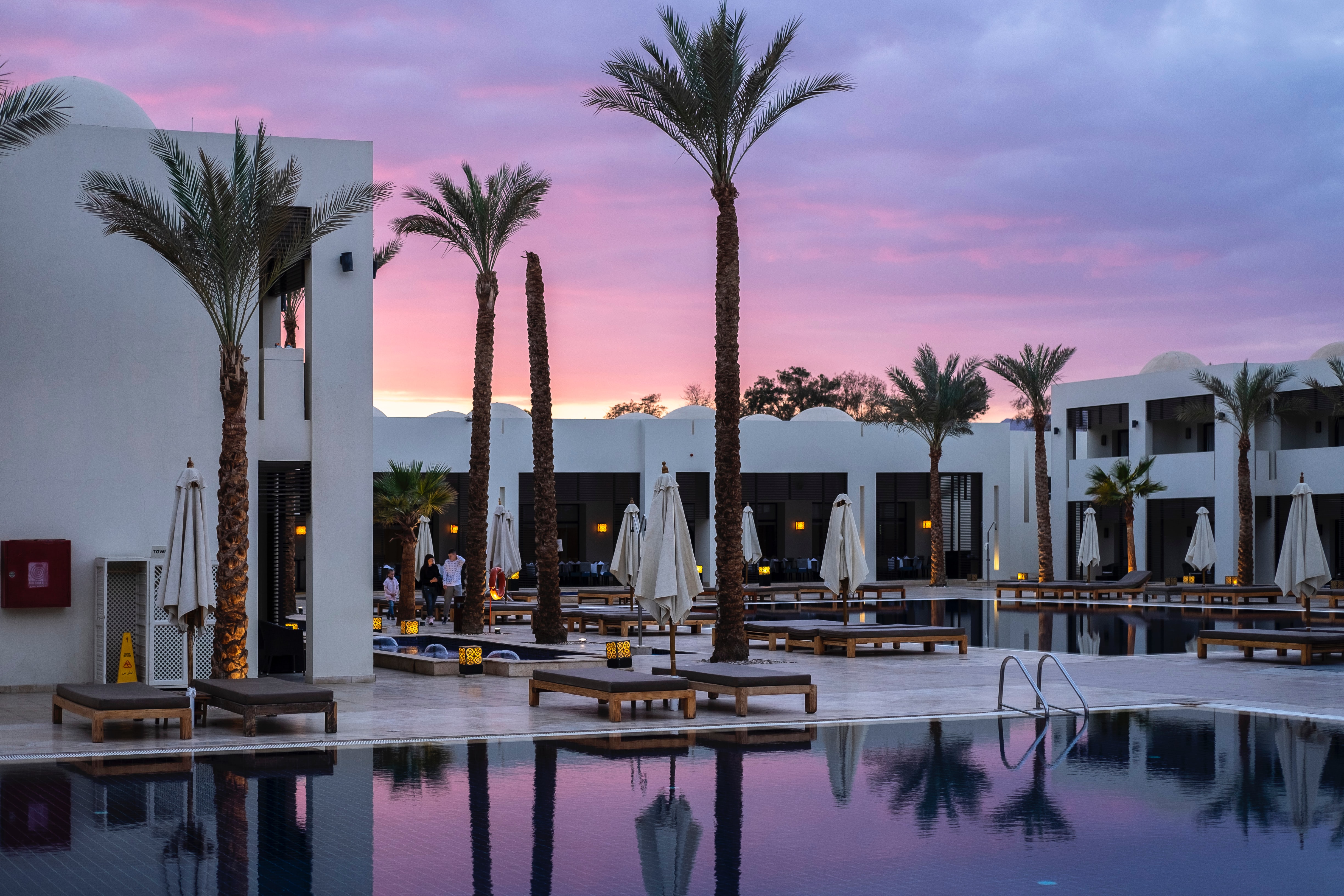 Hotel di lusso al tramonto con piscina, palme, sdrai...in pratica tutti in comfort che accetterebbe qualunque persona